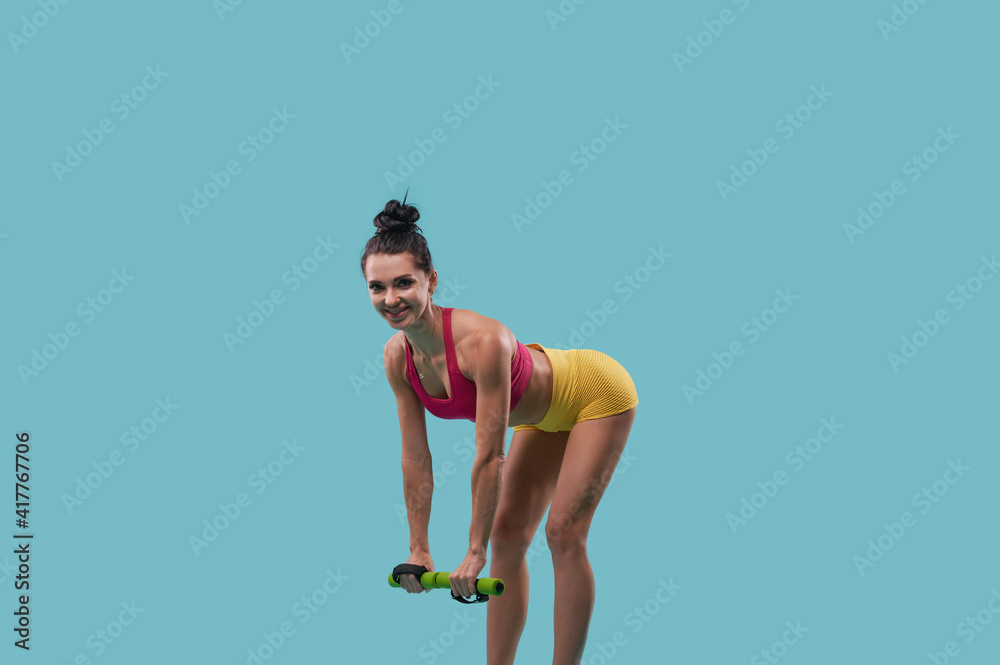 Sexy female fitness instructor exercising with dumbbells on blue background with copy space for promotion. Sexy female fitness instructor exercising with dumbbells on blue background with copy space for promotion.