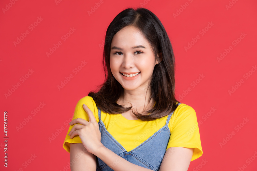 Asian girl Wear yellow shirt and short skirt pose in advertising and presenting goods and contents gesture with friendly smile face on red background. Asian girl Wear yellow shirt and short skirt pose in advertising and presenting goods and contents gesture with friendly smile face on red background.