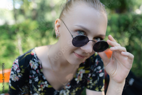 A girl wearing black sunglasses outside looking at the camera
