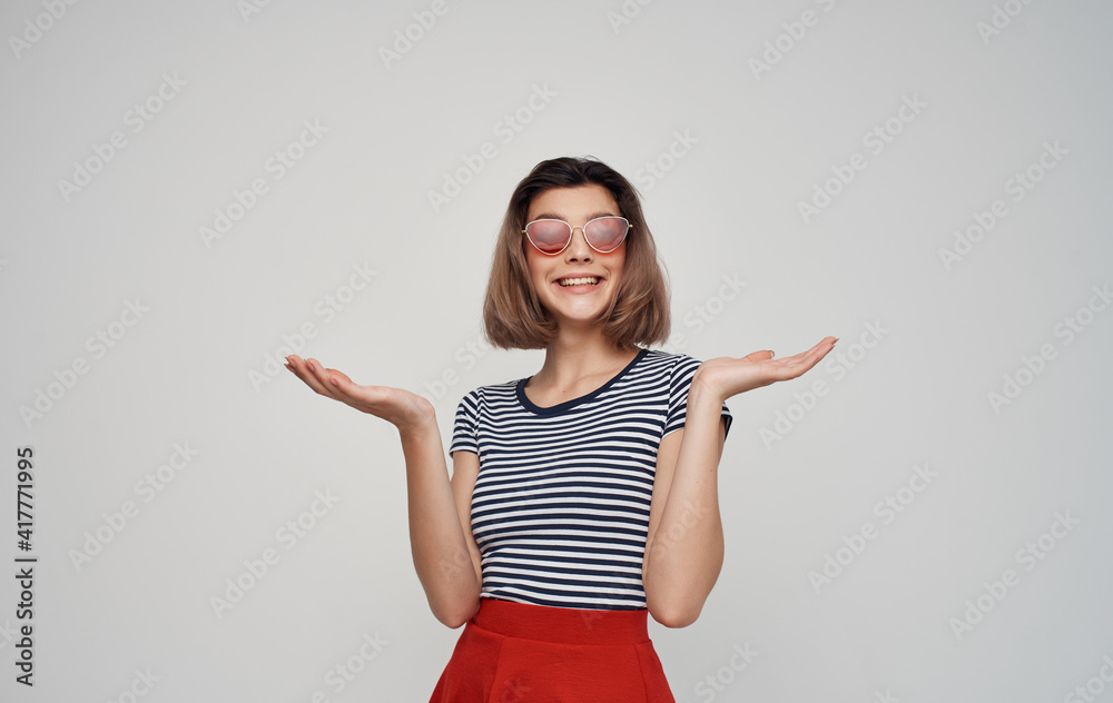 portrait of a woman with glasses and a striped t-shirt on a gray background fashion style red skirt portrait of a woman with glasses and a striped t-shirt on a gray background fashion style red skirt