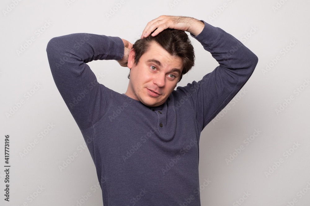 Portrait of handsome young man combing his hair in bathroom of grey background. Portrait of handsome young man combing his hair in bathroom of grey background.