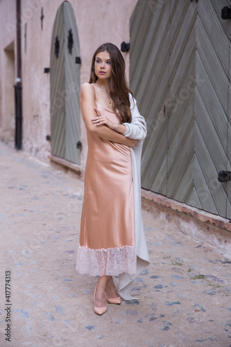A beautiful woman in a light summer gown on the background of an old town.