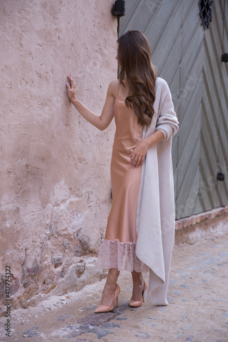A beautiful woman in a light summer gown on the background of an old town.