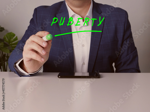 Merchant writing PUBERTY on screen by a green pen photo
