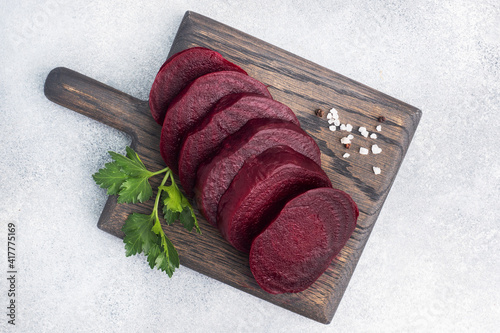 Slices of boiled beetroot on a cutting Board with parsley leaves on a wooden rustic background. Copy space