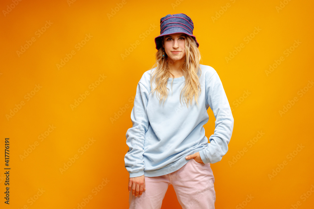 Portrait of a young woman hipster wearing panama hat against yellow background
