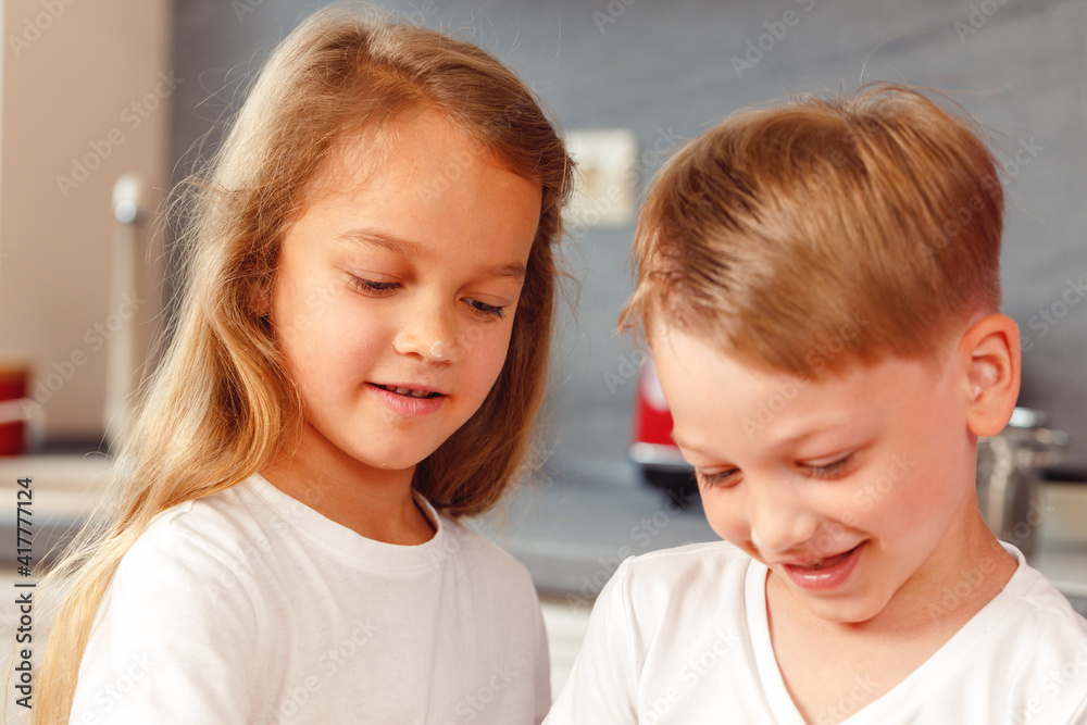 Smiling little girl and boy looking down at something Smiling little girl and boy looking down at something