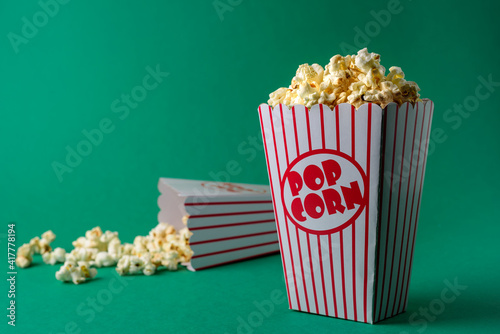 Popcorn in striped box on green background