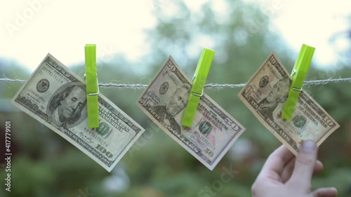 Dollars hang on a linen rope, a hand checks the dried money-the concept of money laundering.