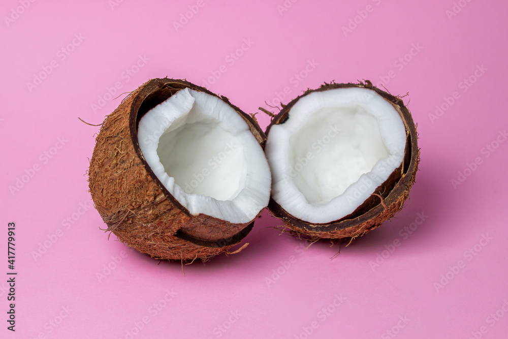 Isolated coconut on a pink background. The two halves of the coconut are in the center of the image. Healthy fruit