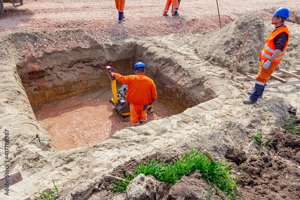 Worker compacting foundation using vibration plate compactor Worker compacting foundation using vibration plate compactor