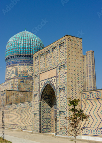 Street view of beautiful ancient Bibi Khanum or Khanym mosque with blue tile dome and gate in UNESCO listed Samarkand, Uzbekistan