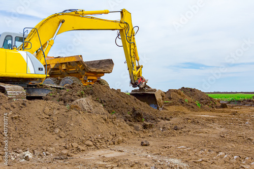 Excavator is loading a truck with ground on building site