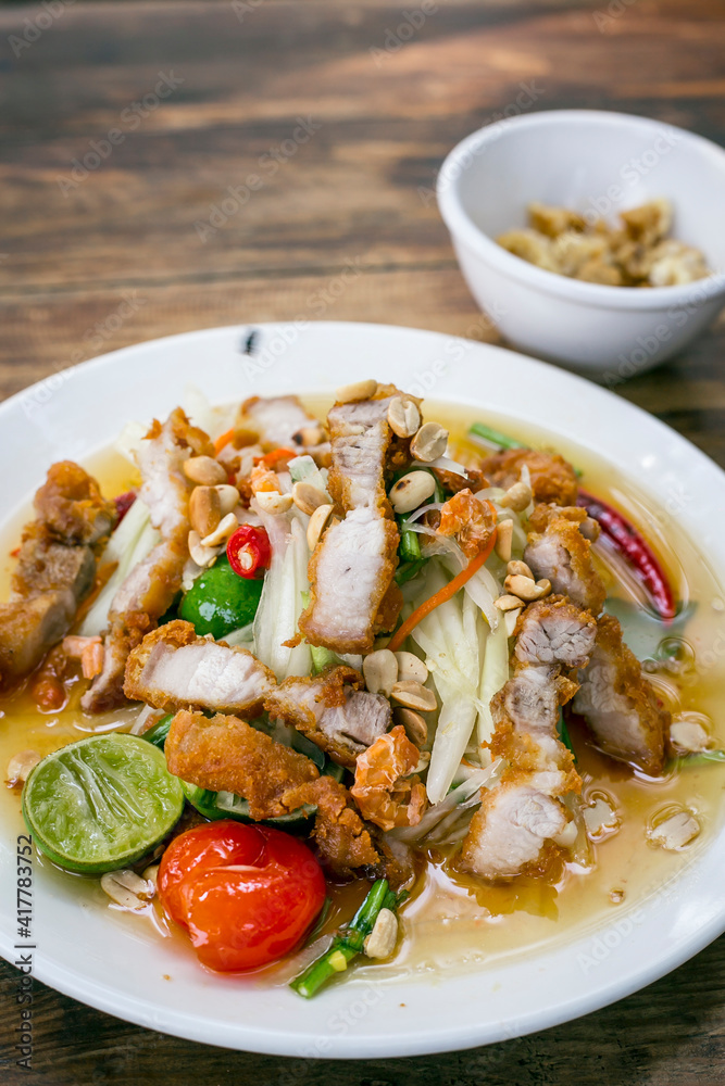 Famous Thai food, papaya salad, Somtum, Papaya Pok Pok. Closeup Thai Green Papaya Salad with Fried pork