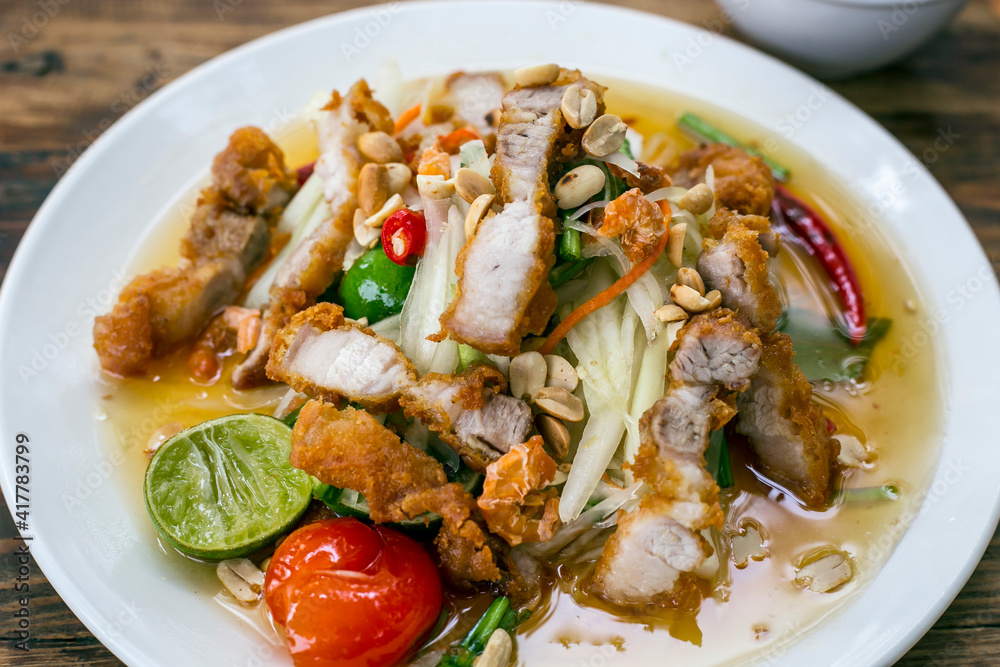 Famous Thai food, papaya salad, Somtum, Papaya Pok Pok. Closeup Thai Green Papaya Salad with Fried pork