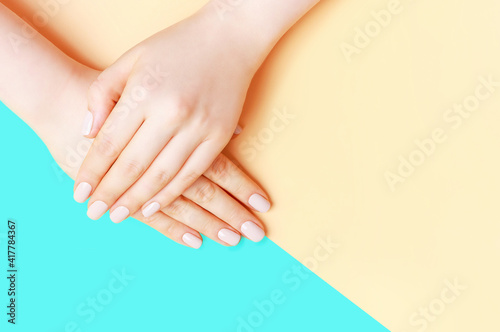 Female hands with a brown manicure on blue background  copy space