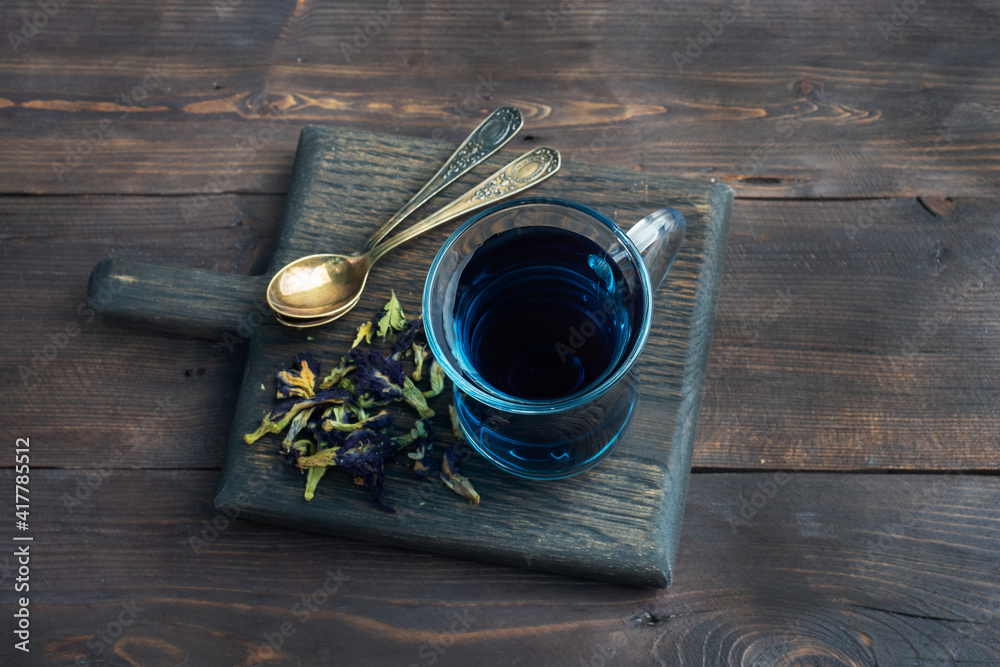 Thai blue tea anchan of buds klitoria Ternate in a glass cup, dark background. Copy space