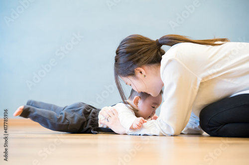室内で、赤ちゃんと遊ぶお母さん