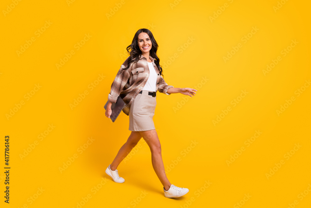 Photo of lovely lady step beaming shiny smile wear plaid jacket short skirt shoes isolated yellow color background