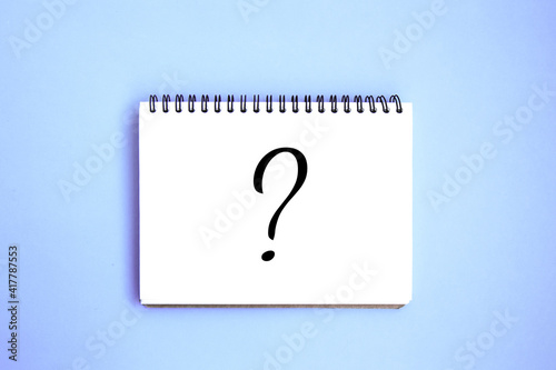 Open notebook with white blank pages on blue background. Notepad with a drawn question mark. Stationery on a blue background with space for text. Minimalism. Flat lay