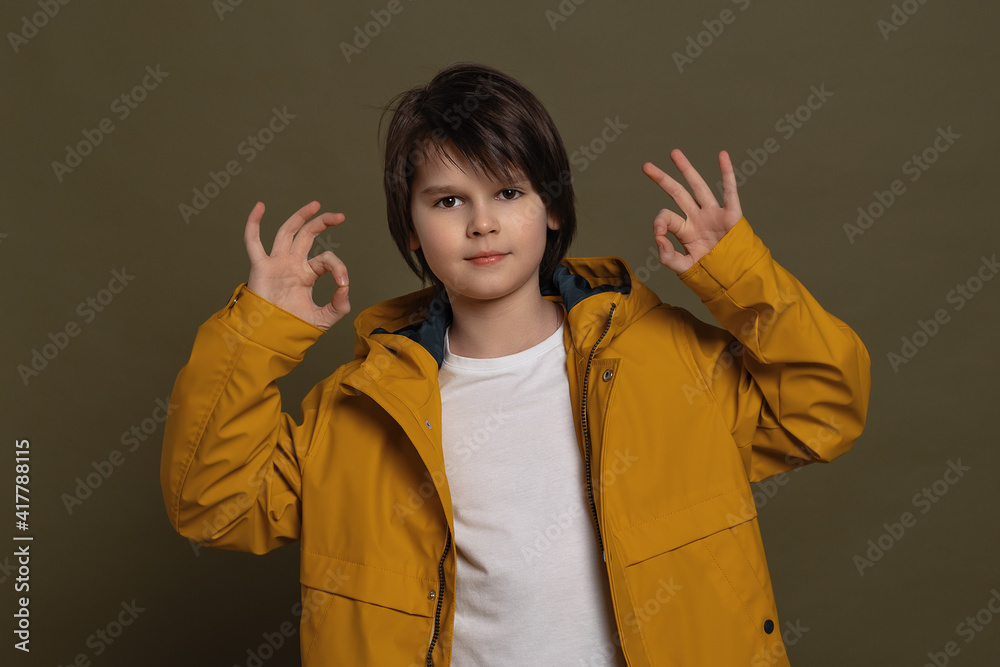 Happy little boy showing OK gesture with hands. Cheerful expression and winner gesture. Studio shot, green background Happy little boy showing OK gesture with hands. Cheerful expression and winner gesture. Studio shot, green background