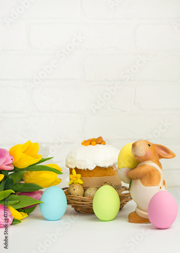 Easter  bunny  and Eastr cake   on white background  with  bouquet yellow tulip  and copy space .  vertical .Happy Easter  morning Holidays concept. photo