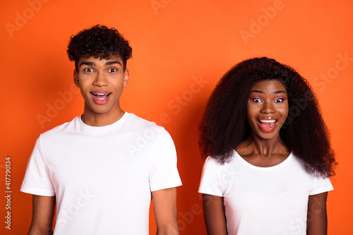 Photo of young happy excited amazed shocked afro couple see big sale discount isolated on orange color background