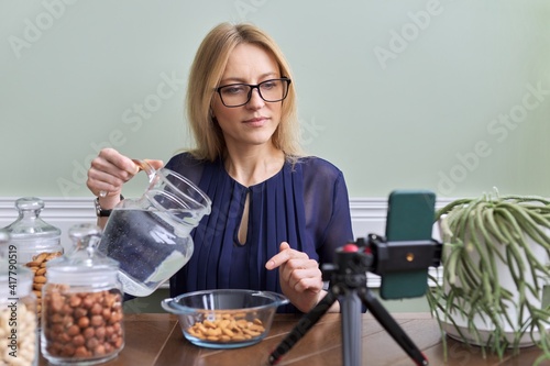 Activation of vitamins and minerals in nuts. Woman nutritionist soaking nuts in water photo