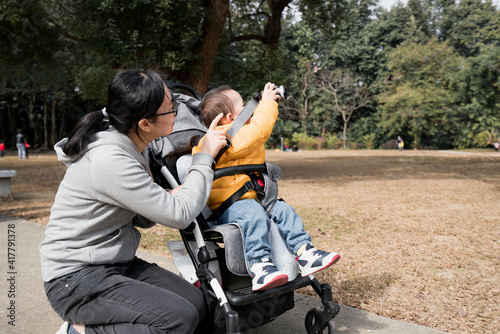 An Asian mother takes her son to the park to take pictures