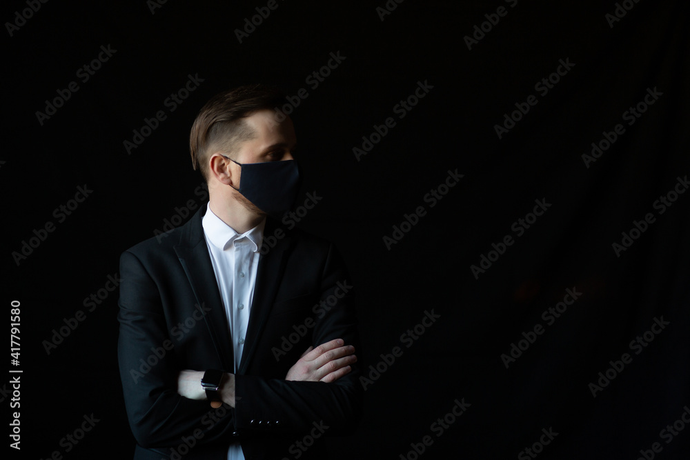 Portrait of attractive man wearing black suit and protective mask for prevention Covid-19 isolated over black background Portrait of attractive man wearing black suit and protective mask for prevention Covid-19 isolated over black background