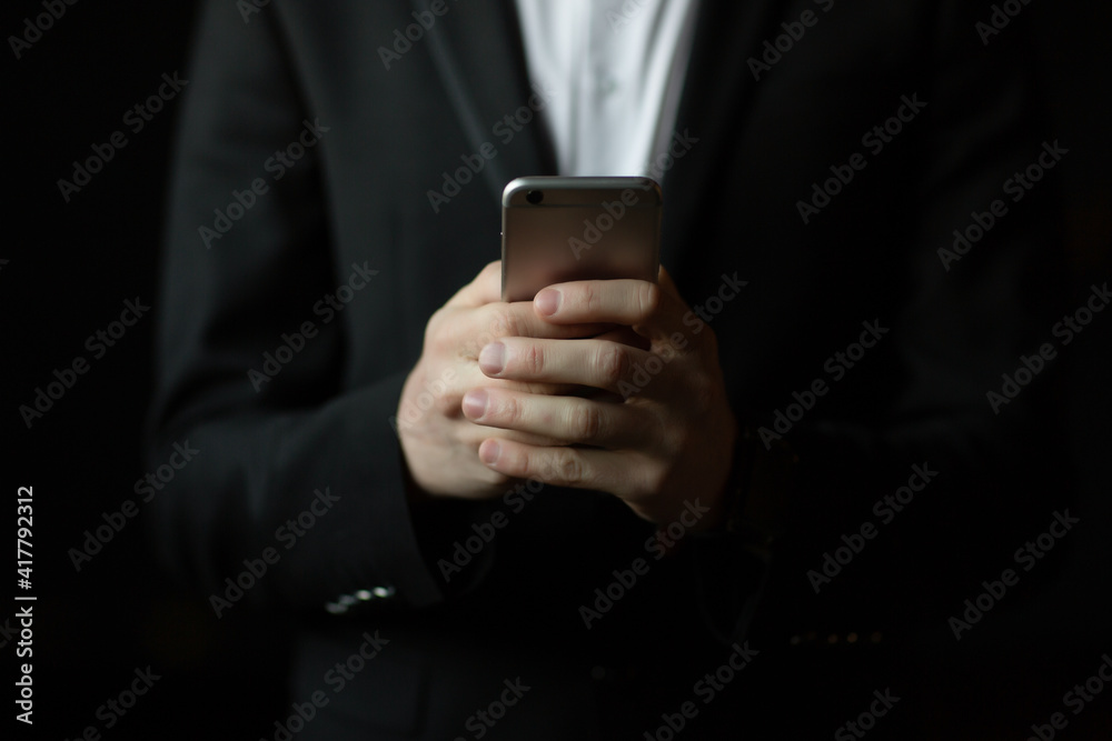 Cropped close up shot of man's hands holding smartphone on black background. Cropped close up shot of man's hands holding smartphone on black background.