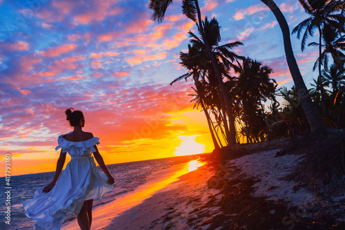 silhouette of a woman in a fluttering dress by the ocean at sunrise