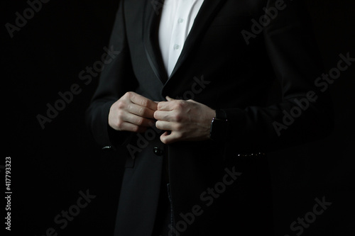 Business man button his jacket on black background. Man in business suit. 