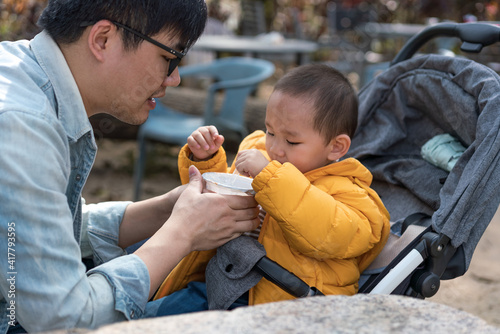 An Asian father takes his son to the park to share food