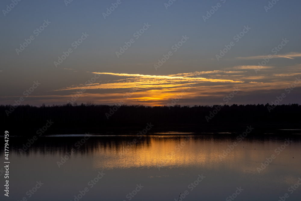 Dramatic and colorful sunset over a forest lake reflected in the water. Blakheide, Beerse, Belgium. High quality photo