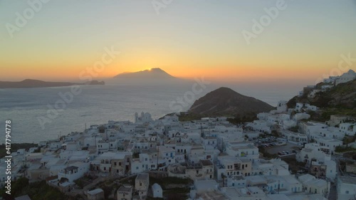 Flying Past White Houses in Plaka Village and Sun Setting Behind Mountain photo