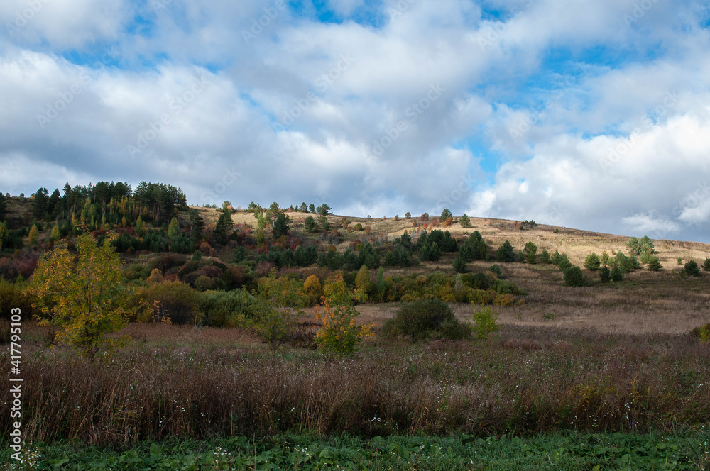 Autumn landscape. Yellow trees, blue sky with white clouds.