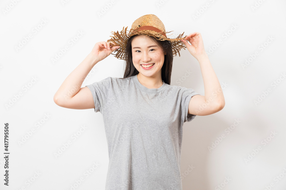 Cheerful and young Asian woman with straw hat and grey t-shirt on white background. Cheerful and young Asian woman with straw hat and grey t-shirt on white background.