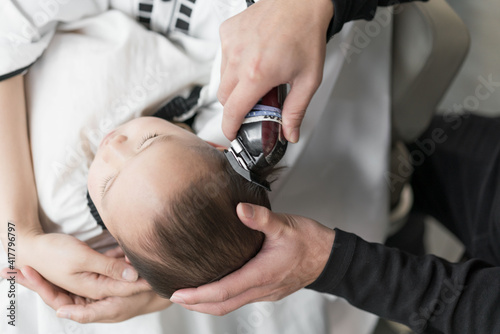 Asian mothers with their sons in their arms are having their hair cut