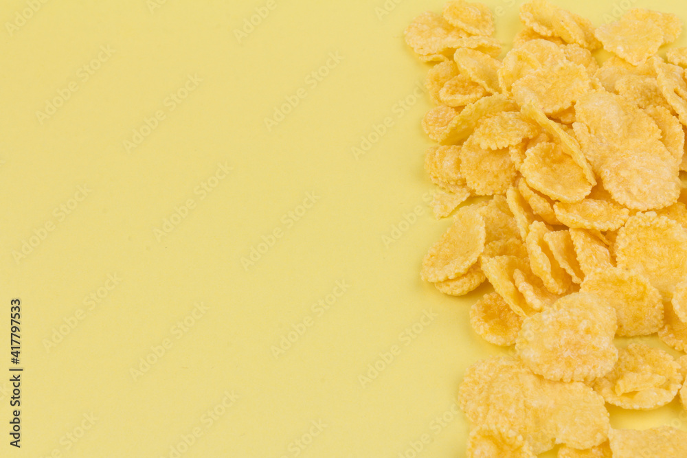 Obraz premium Pile of yellow cornflakes on yellow background