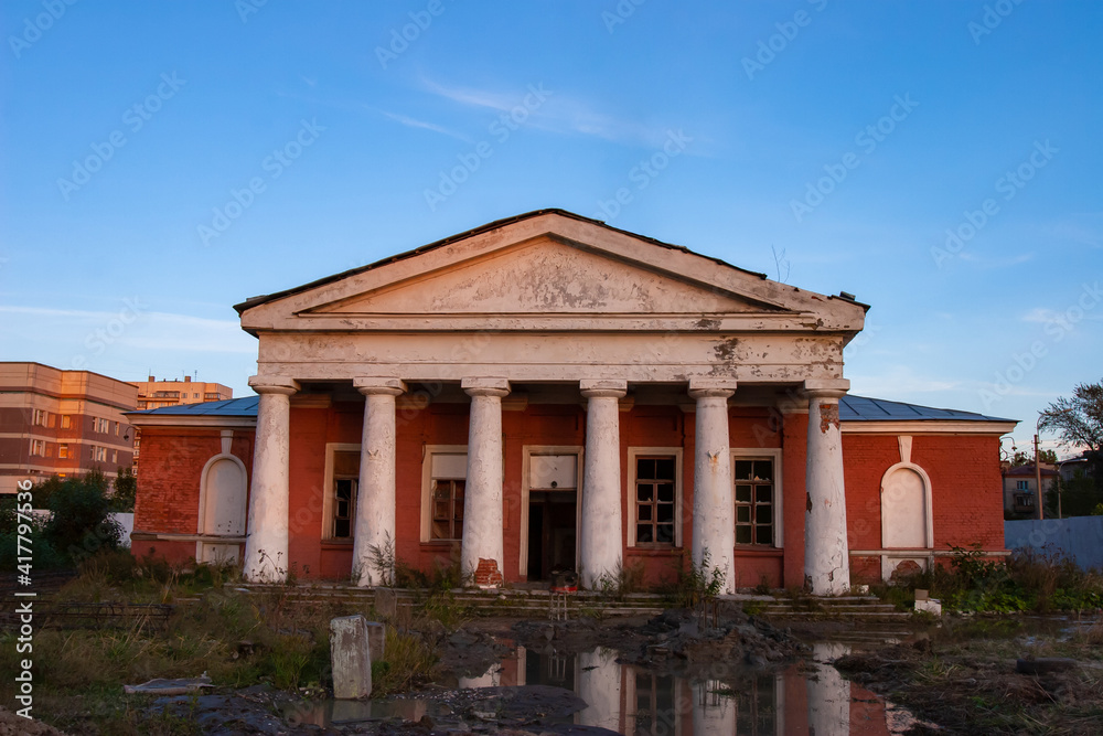 Abandoned building with columns. Concept - was abandoned due to bankruptcy of company. Dilapidated building without windows and doors. House is gradually crumbling from old age. Blue sky background