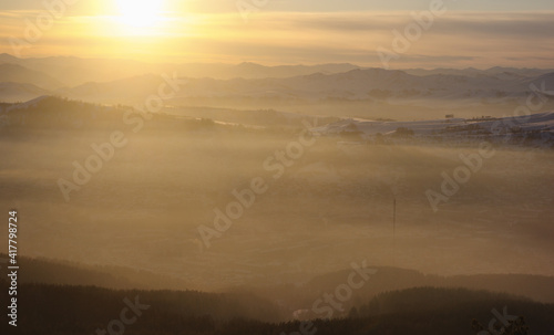 Winter sunset snow mist mountain view on the background of hills under colorful sky