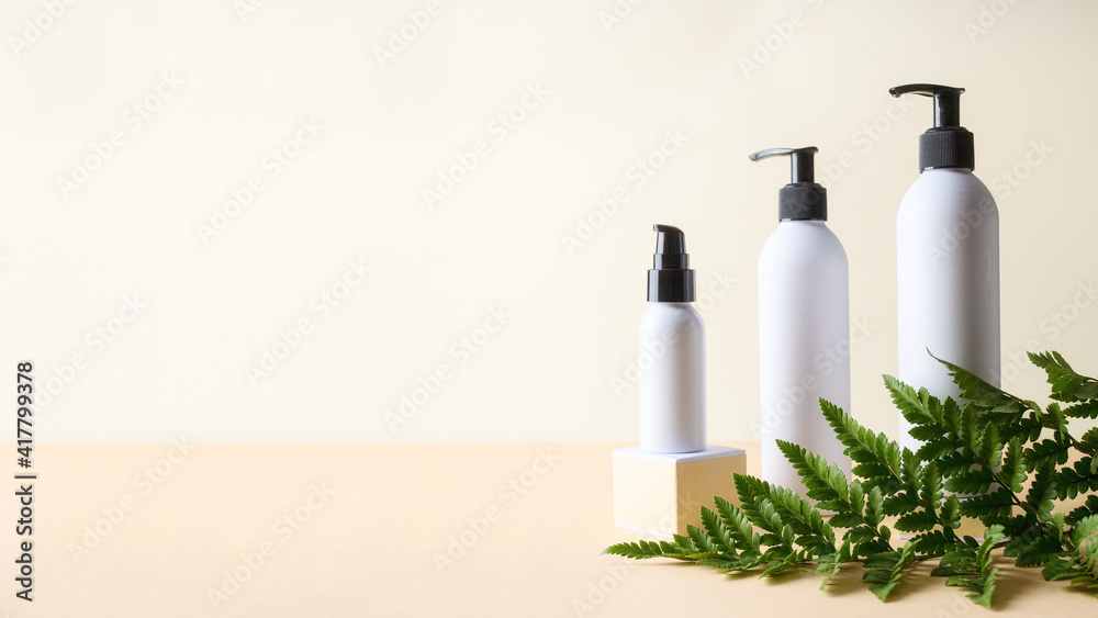 White cosmetic bottles on podium with green plant. Large banner for cosmetic product presentation and branding. Natural product for skin care concept.