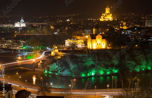 view of the night city with colourful lighted bank of the river and big church on the hill