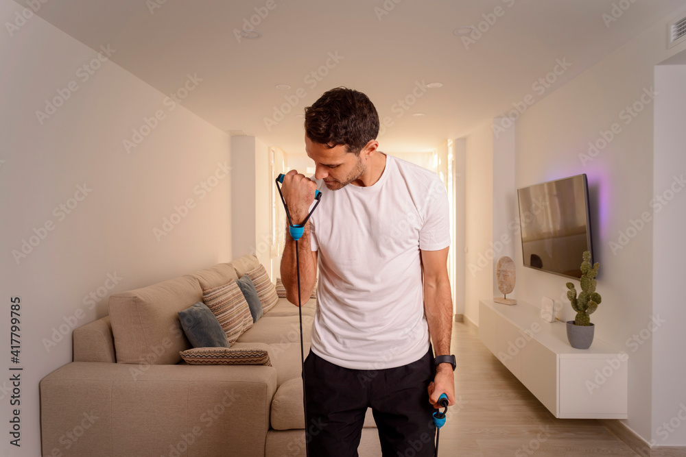 portrait of sporty man doing biceps workout with elastic resistance bands at home portrait of sporty man doing biceps workout with elastic resistance bands at home