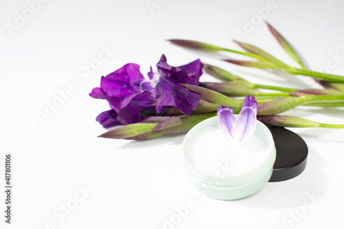 Iris flowers and a jar of cream are on a white background. Natural cosmetics theme. Free space for text.