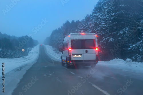 minibus moves in winter in blizzard along snow-covered road