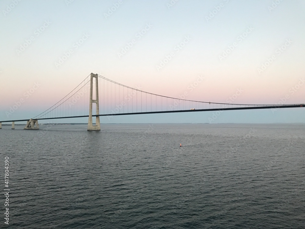 Brücke Hängebrücke Spannbeton Hohlkastenbrücke Storebæltsbroen Brückenzug in Dänemark in der Meerenge Großer Belt zwischen den Inseln Fünen und Seeland von einem Kreuzfahrtschiff bei Sonnenuntergang Brücke Hängebrücke Spannbeton Hohlkastenbrücke Storebæltsbroen Brückenzug in Dänemark in der Meerenge Großer Belt zwischen den Inseln Fünen und Seeland von einem Kreuzfahrtschiff bei Sonnenuntergang