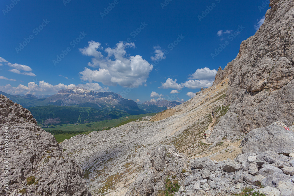 Path at the base of a wall with the Dolomite panorama of Sella massif in the background, Settsass, Dolomites, Italy