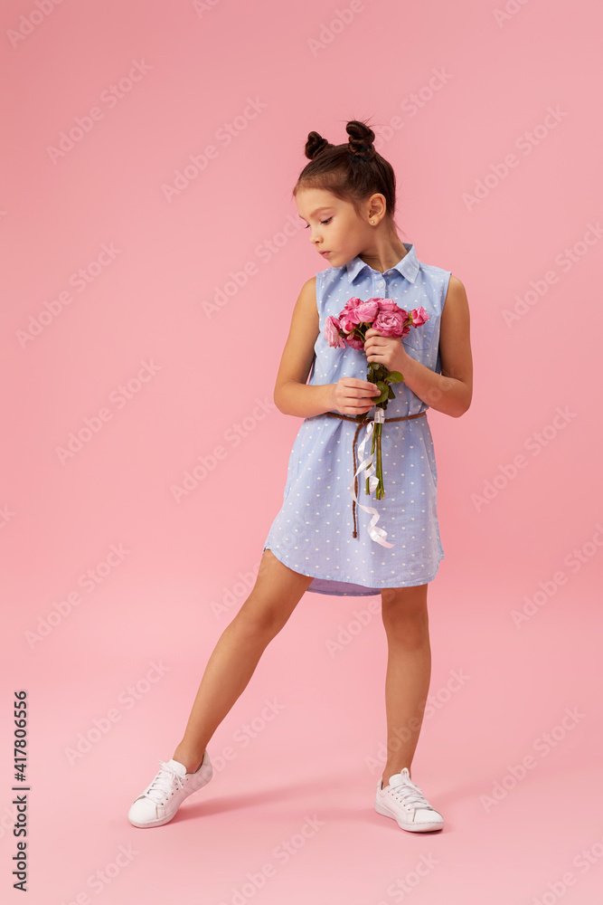 adorable little child girl holding bouquet of roses on pink background. adorable little child girl holding bouquet of roses on pink background.